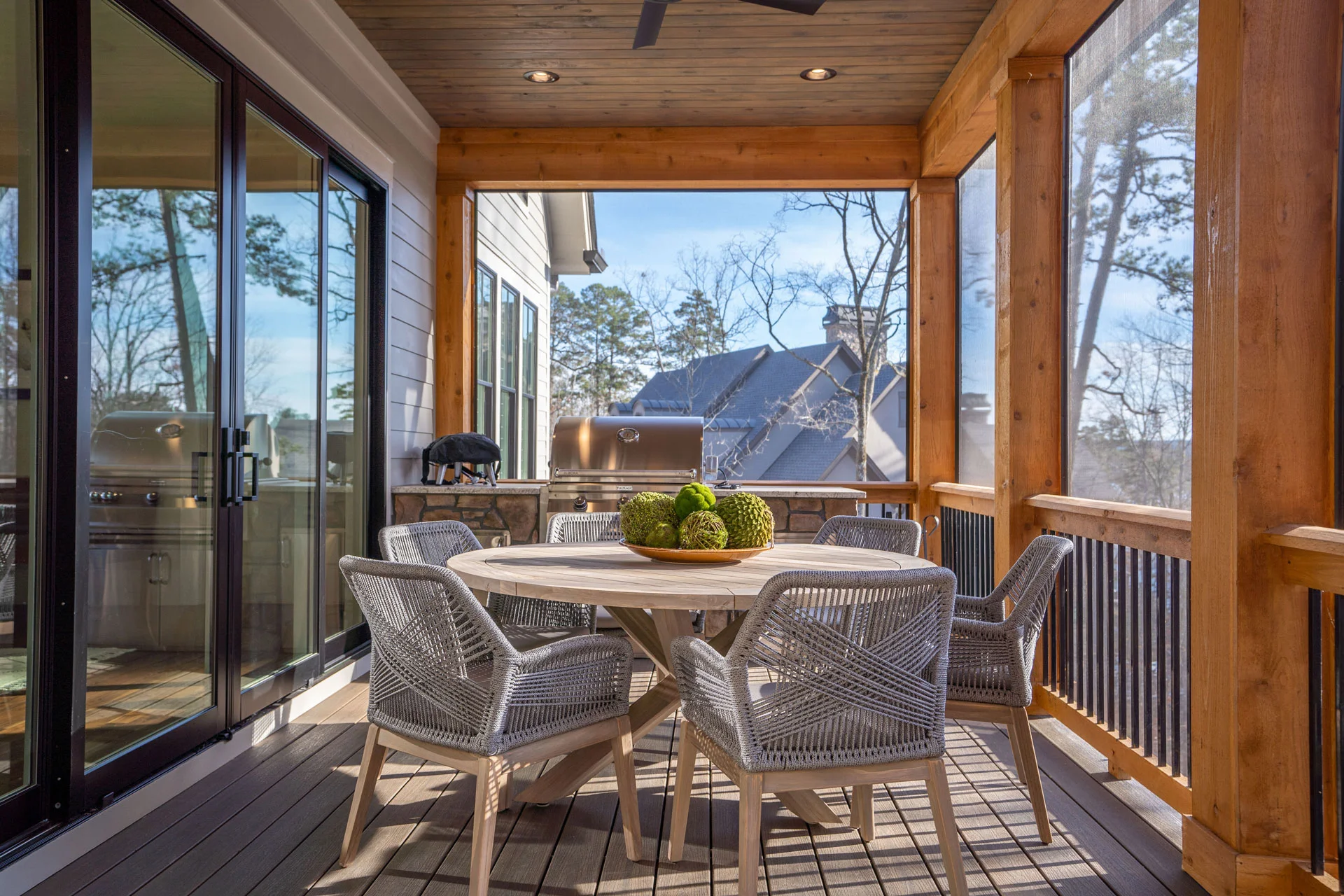 image of cozy style outdoor living area with woven 5 chairs and wooden table - custom home builder | Southern Luxury Homes