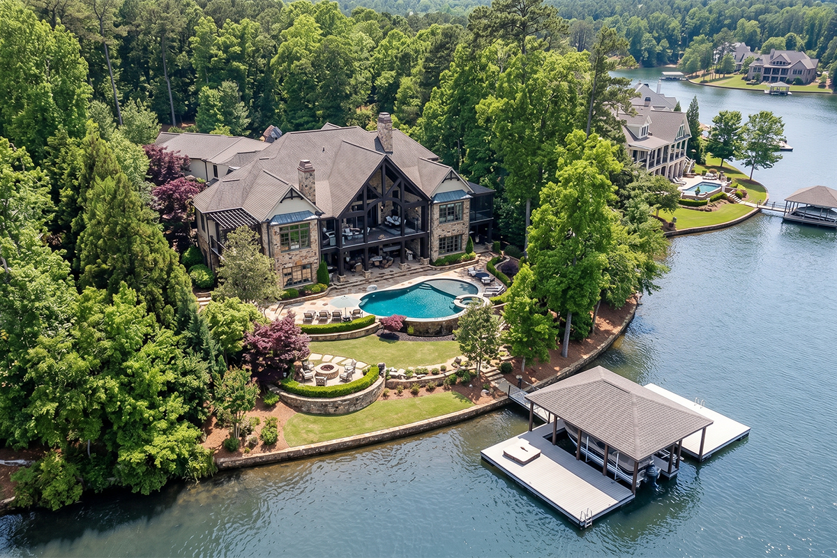 Aerial view of Southern Luxury lakefront estate with pool, boat dock, and stone exterior