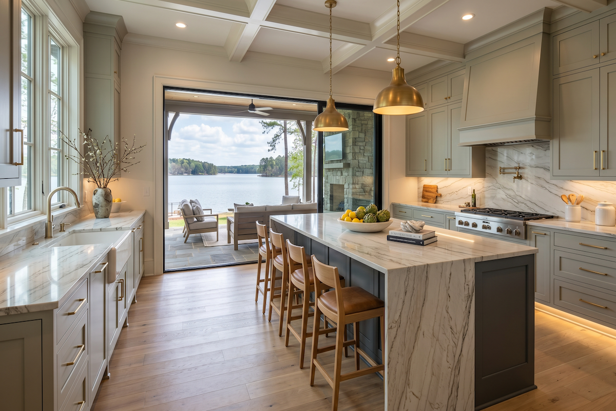 Luxury lake house kitchen with marble island, sage green cabinets, and panoramic lake views